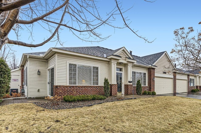 single story home featuring a garage, driveway, a shingled roof, brick siding, and a front yard