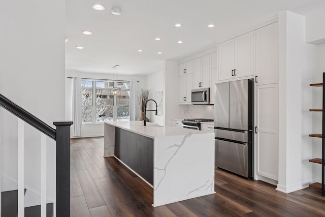 kitchen featuring dark wood-style floors, appliances with stainless steel finishes, white cabinetry, and light stone countertops