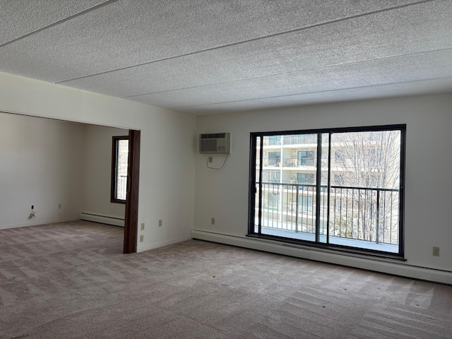 carpeted empty room featuring baseboard heating, a textured ceiling, and baseboards