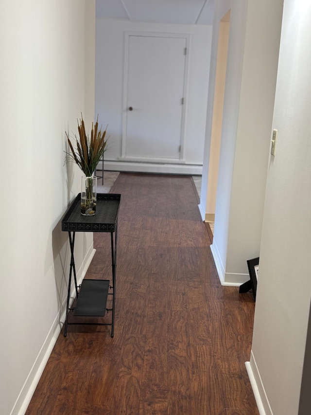 hall with a baseboard heating unit, baseboards, and wood finished floors