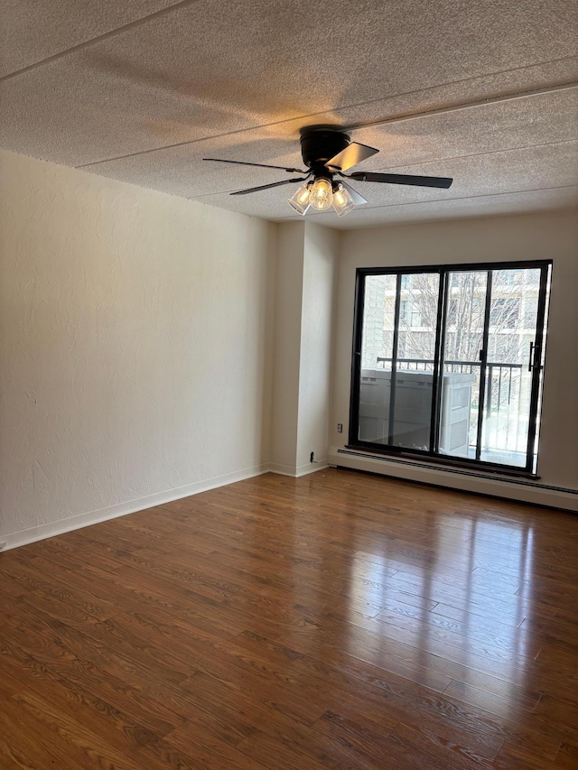 spare room with dark wood finished floors, a textured ceiling, and a baseboard heating unit