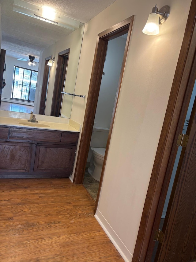 bathroom featuring vanity, wood finished floors, ceiling fan, a textured ceiling, and toilet