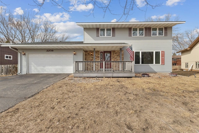 traditional-style home with a porch, driveway, and a garage