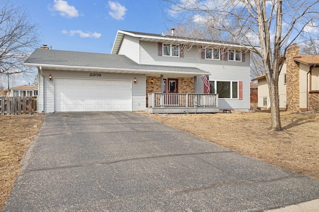 traditional home with driveway, fence, covered porch, a shingled roof, and a garage