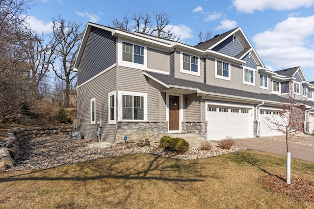 view of front of home featuring driveway, stone siding, a front lawn, and an attached garage