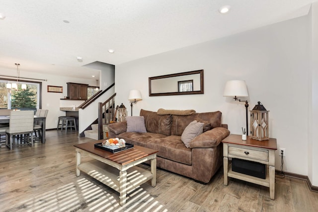 living room featuring recessed lighting, an inviting chandelier, light wood-type flooring, baseboards, and stairs