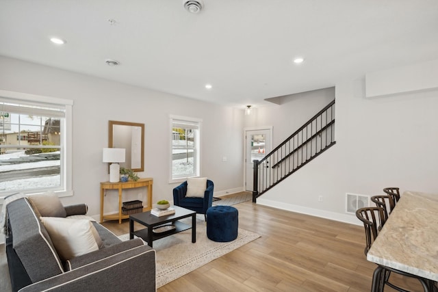 living room featuring light wood finished floors, plenty of natural light, stairs, and recessed lighting