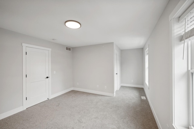 carpeted empty room with visible vents and baseboards