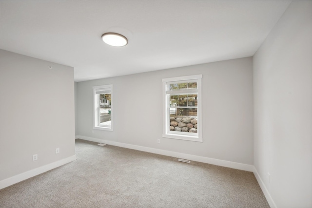 spare room featuring carpet and baseboards