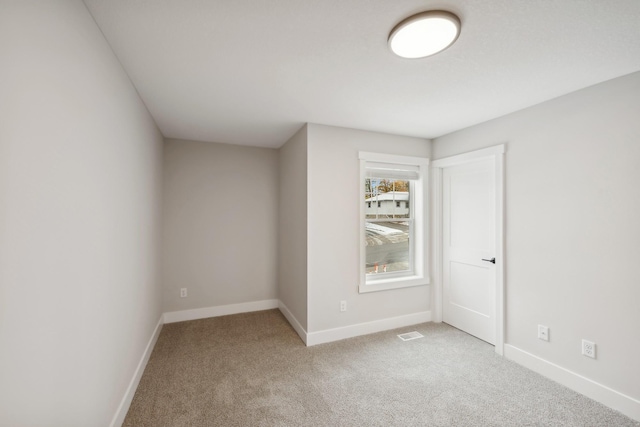 carpeted empty room featuring visible vents and baseboards