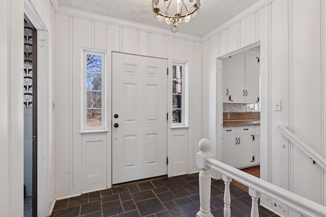 2148 Delaware Ave, Sunfish Lake, MN 55118 - foyer entrance featuring crown molding, a textured ceiling, a decorative wall, a chandelier, and dark stone finish floors