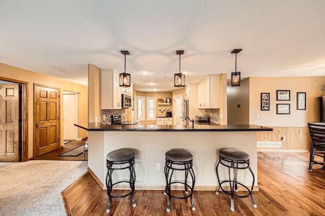 13847 Taconite St NE, Ham Lake, MN 55304 - kitchen with stainless steel appliances, a kitchen breakfast bar, dark countertops, dark wood-style floors, and a peninsula