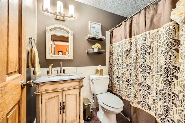 13847 Taconite St NE, Ham Lake, MN 55304 - full bathroom featuring tile walls, a wainscoted wall, toilet, vanity, and a textured ceiling