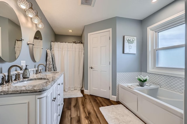 13847 Taconite St NE, Ham Lake, MN 55304 - bathroom featuring a bath, wood finished floors, double vanity, recessed lighting, and baseboards