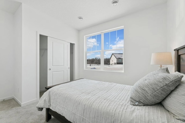 carpeted bedroom with a closet, a textured ceiling, and baseboards