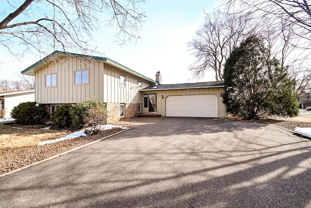 view of front facade with an attached garage, brick siding, board and batten siding, and driveway