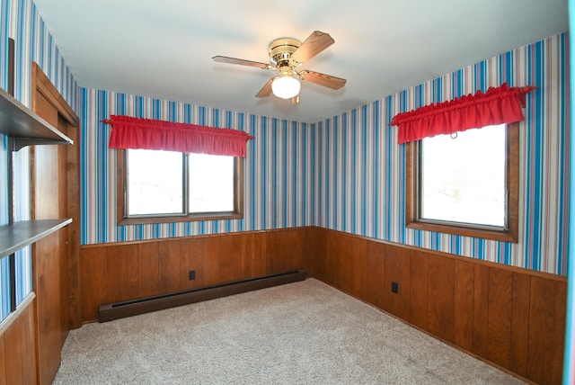 unfurnished room with wallpapered walls, carpet floors, wainscoting, a ceiling fan, and a baseboard radiator