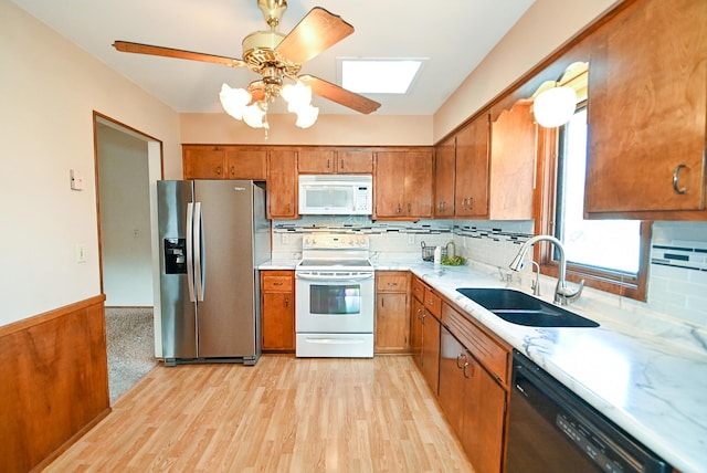 kitchen with brown cabinetry, appliances with stainless steel finishes, light countertops, and a sink