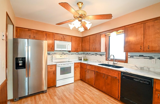 kitchen with brown cabinetry, white appliances, light countertops, and a sink