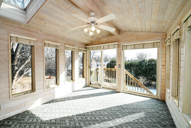 unfurnished sunroom featuring lofted ceiling with skylight, wooden ceiling, and a ceiling fan