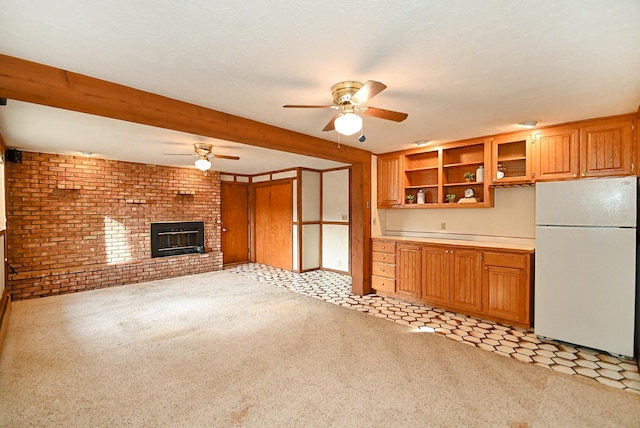 unfurnished living room featuring brick wall, a brick fireplace, ceiling fan, light carpet, and beam ceiling