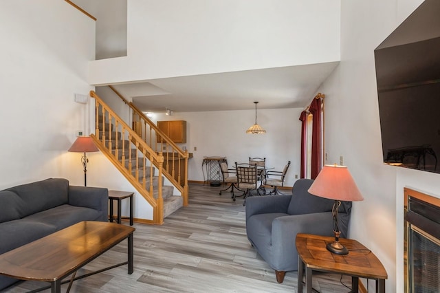 living area with stairs, a high ceiling, a fireplace, and light wood finished floors