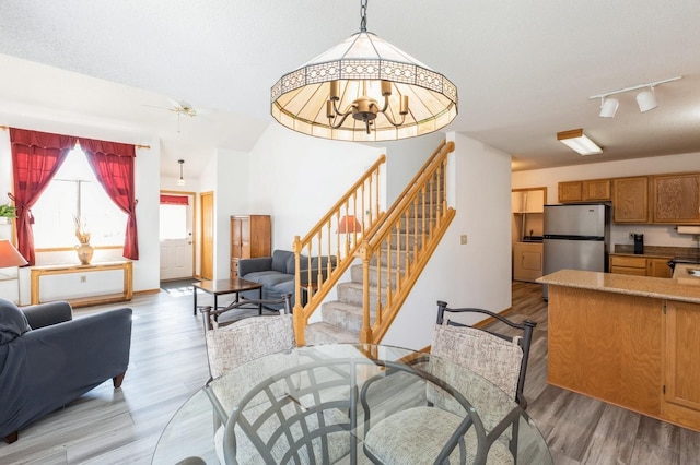 living area featuring stairway, a textured ceiling, light wood-style flooring, and rail lighting