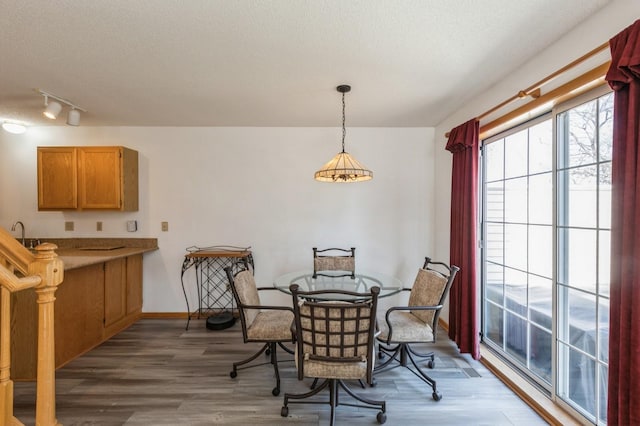 dining space with baseboards, a textured ceiling, and wood finished floors