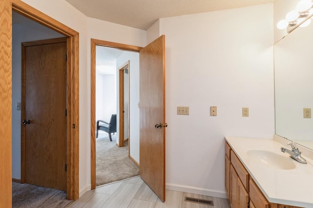 bathroom featuring visible vents, baseboards, and vanity