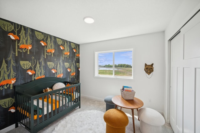 carpeted bedroom featuring a crib and baseboards