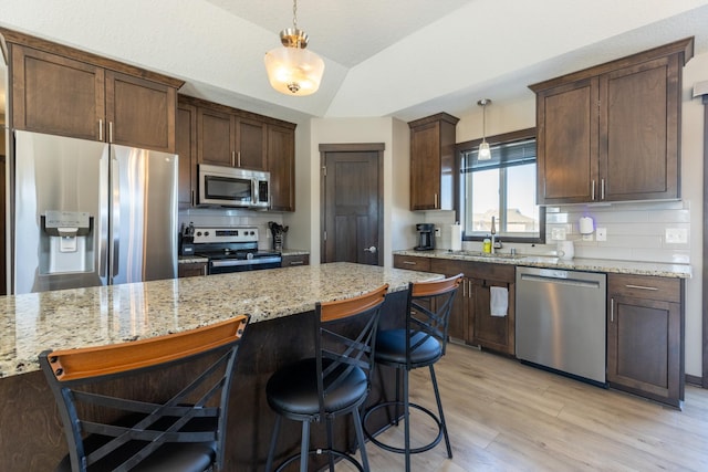 kitchen with stainless steel appliances, tasteful backsplash, light wood-style flooring, and pendant lighting