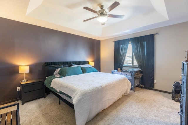 bedroom featuring light carpet, ceiling fan, baseboards, and a raised ceiling