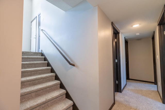 stairs with carpet, a textured ceiling, and baseboards