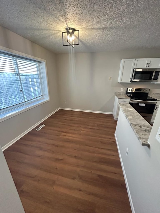 kitchen featuring dark wood-style floors, visible vents, appliances with stainless steel finishes, white cabinetry, and baseboards