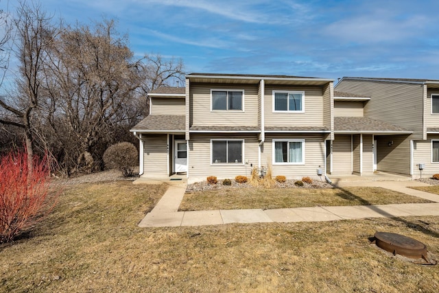 view of property featuring a front yard and a shingled roof