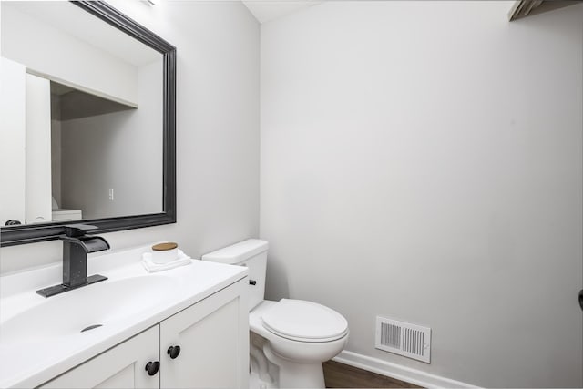 bathroom featuring visible vents, toilet, wood finished floors, baseboards, and vanity