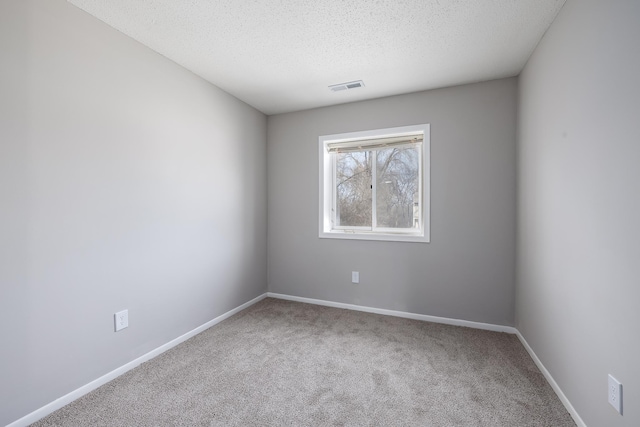 spare room with visible vents, carpet flooring, a textured ceiling, and baseboards