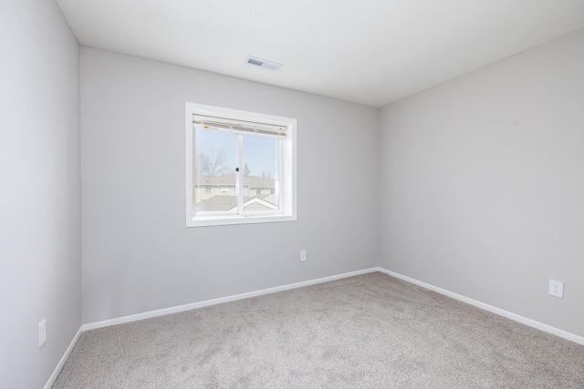 carpeted spare room with visible vents and baseboards