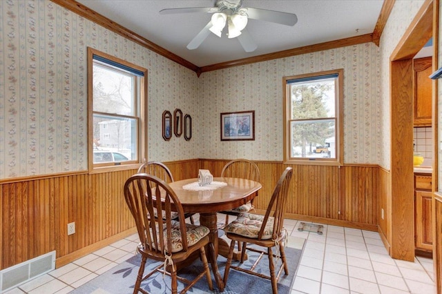 dining area featuring a wainscoted wall, a healthy amount of sunlight, visible vents, and wallpapered walls