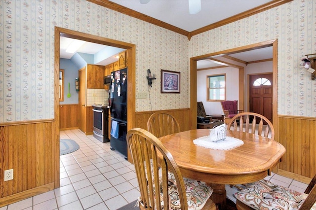 dining room featuring a wainscoted wall, crown molding, light tile patterned flooring, wood walls, and wallpapered walls