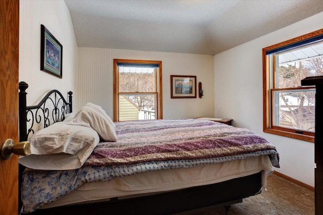 bedroom featuring lofted ceiling, carpet floors, multiple windows, and baseboards