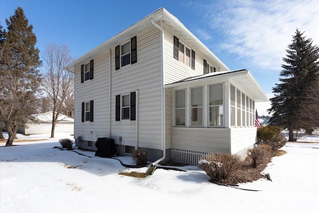 view of snowy exterior featuring a sunroom