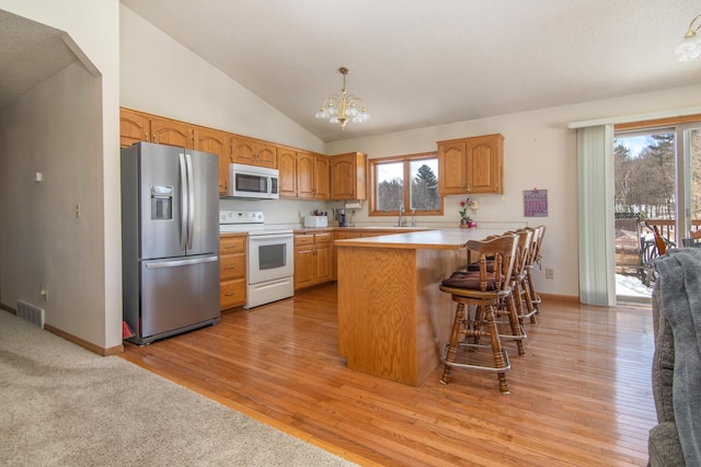 kitchen featuring white appliances, visible vents, a peninsula, a chandelier, and a sink