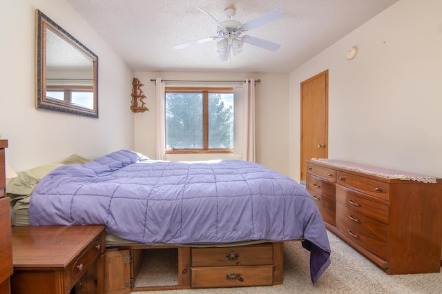 bedroom with light carpet, a ceiling fan, and a textured ceiling