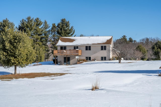 snow covered rear of property with a deck