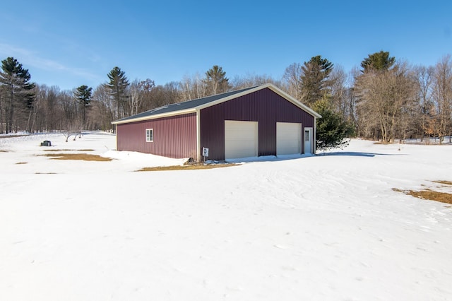 snow covered garage with a detached garage