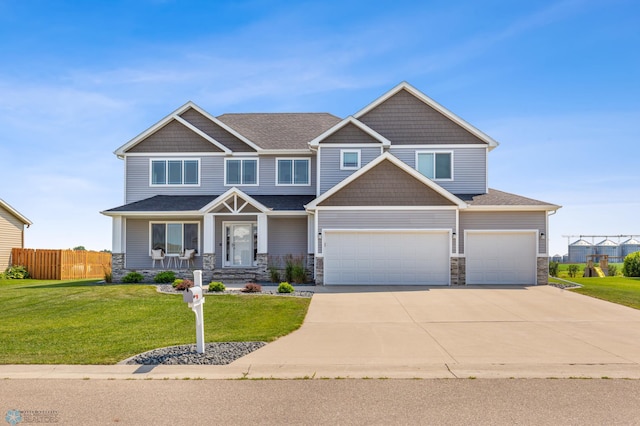 craftsman-style home with concrete driveway, fence, a garage, stone siding, and a front lawn