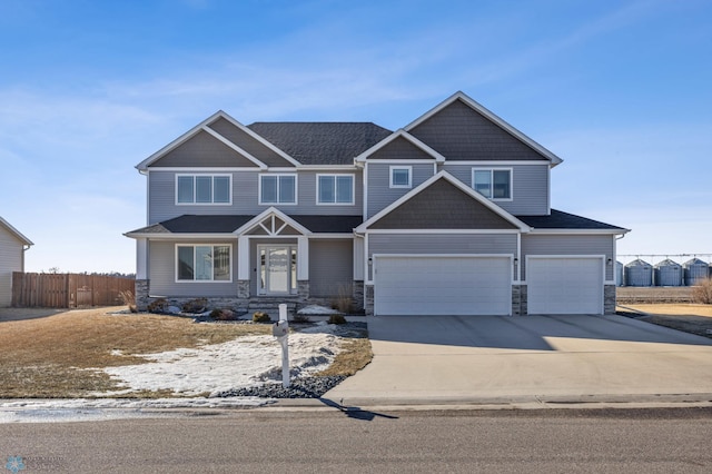 craftsman-style home featuring driveway, stone siding, an attached garage, and fence