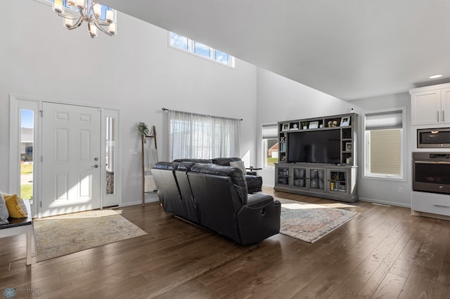 living room featuring a towering ceiling, baseboards, dark wood finished floors, and a notable chandelier