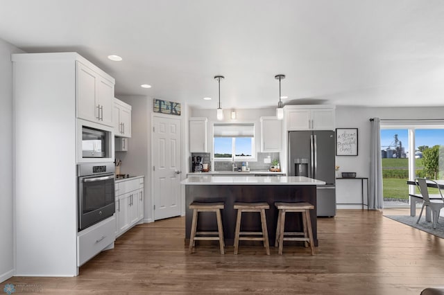 kitchen with a healthy amount of sunlight, appliances with stainless steel finishes, decorative backsplash, and a center island